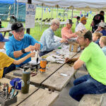Bill, John and Denny are lined up at the tying tables working with the kids.